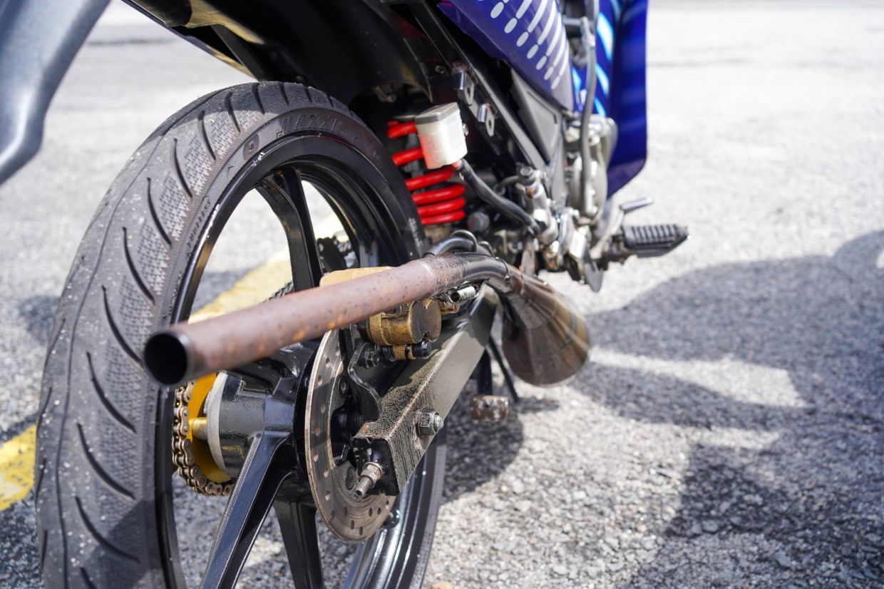 JPJ officer inspecting a motorcycle with a non-compliant registration plate at a roadblock.